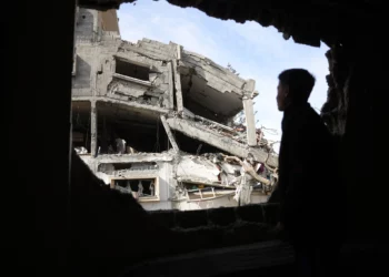 Un joven palestino mira por la ventana de un edificio dañado tras los ataques israelíes nocturnos contra una zona residencial en el distrito de Nazla, en el suroeste de Jabaliya, en el norte de la Franja de Gaza, el 16 de abril de 2025. (Foto de BASHAR TALEB / AFP)