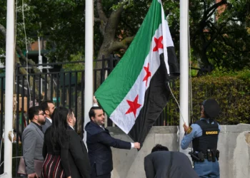 El ministro de Asuntos Exteriores sirio, Asaad al-Shaibani, iza la nueva bandera siria durante una ceremonia de izamiento de bandera en la sede de las Naciones Unidas en Nueva York el 25 de abril de 2025. (Foto: ANGELA WEISS / AFP)