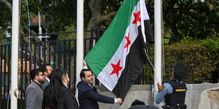 El ministro de Asuntos Exteriores sirio, Asaad al-Shaibani, iza la nueva bandera siria durante una ceremonia de izamiento de bandera en la sede de las Naciones Unidas en Nueva York el 25 de abril de 2025. (Foto: ANGELA WEISS / AFP)