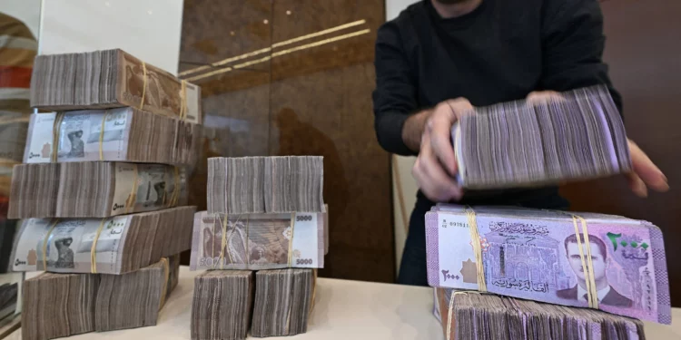 Un empleado de una casa de cambio apila billetes sirios en una tienda de Damasco el 16 de abril de 2025. (LOUAI BESHARA / AFP)