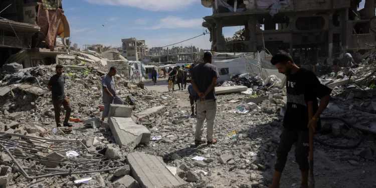 La gente inspecciona los daños entre los escombros de un edificio alcanzado por un ataque israelí en Jabaliya, en el norte de la Franja de Gaza, el 15 de mayo de 2025. (BASHAR TALEB / AFP)