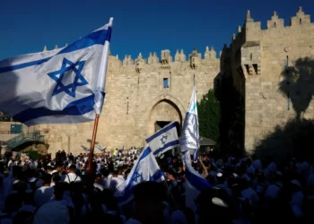 Activistas israelíes se reúnen con banderas nacionales israelíes frente a la Puerta de Damasco de la Ciudad Vieja de Jerusalén el 5 de junio de 2024, durante la marcha de las banderas del Día de Jerusalén. (Menahem Kahana / AFP)