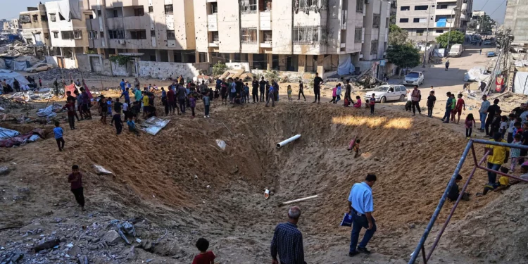 Palestinos se reúnen alrededor de un cráter causado por un ataque israelí contra un campamento de desplazados en la ciudad de Gaza, el 28 de junio de 2025. (AP/Jehad Alshrafi)