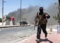 Una densa humareda se eleva mientras un miembro de las fuerzas beduinas y tribales corre durante los enfrentamientos con combatientes drusos en la ciudad de Sweida, en el sur de Siria, el 19 de julio de 2025. (OMAR HAJ KADOUR / AFP)