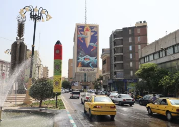 El tráfico fluye en Teherán junto a una enorme valla publicitaria con una pintura de un misil cayendo sobre Israel con el lema en farsi, “El misil ha caído entre los demonios”, el 16 de julio de 2025 (ATTA KENARE / AFP)
