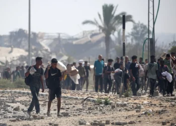 Palestinos desplazados en el campo de refugiados de Nuseirat transportan paquetes de comida y otros artículos que consiguieron en un punto de distribución de ayuda de la GHF en el corredor de Netzarim, en el centro de la Franja de Gaza, el 26 de julio de 2025. (Eyad BABA / AFP)