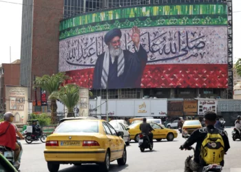 Los conductores pasan junto a una valla publicitaria que representa al líder supremo de Irán, el ayatolá Alí Jamenei, en el centro de la plaza Valiasr de Teherán, el 13 de julio de 2025. (ATTA KENARE / AFP)