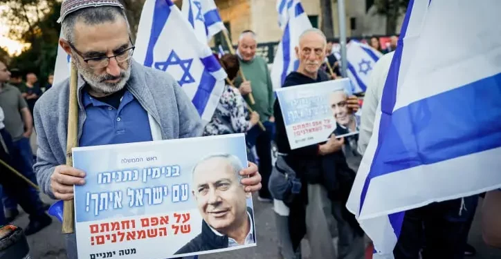 Un israelí asiste a una manifestación en apoyo a la reforma judicial planeada por el gobierno, frente a la Casa Presidencial en Jerusalén, el 3 de abril de 2023. Su pancarta dice: “Benjamín Netanyahu, el pueblo de Israel está contigo, a pesar de la oposición de la izquierda”. (Erik Marmor/Flash90)