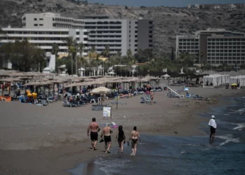 Turistas caminan por la playa frente a los hoteles en la isla egea de Rodas el 29 de agosto de 2020. (Louisa GOULIAMAKI / AFP)