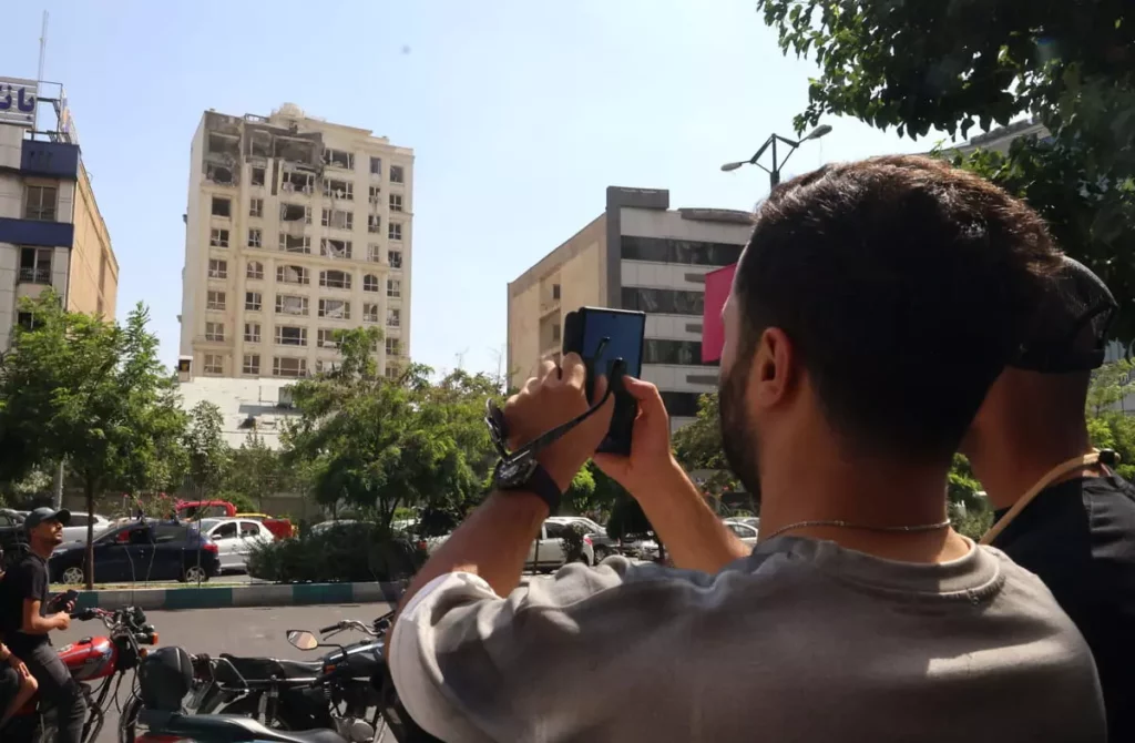 Un hombre toma una foto de un edificio dañado en un ataque israelí contra Teherán el 13 de junio de 2025. (Foto de MEGHDAD MADADI / TASNIM NEWS / AFP)